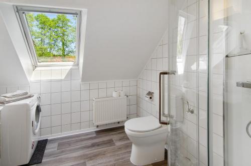 a white bathroom with a toilet and a window at Ferienwohnung Otte in Apen