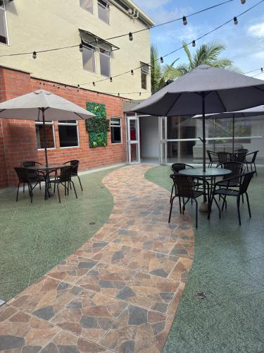 a patio with tables and chairs and umbrellas at Hotel Valle de San Nicolas in Rionegro