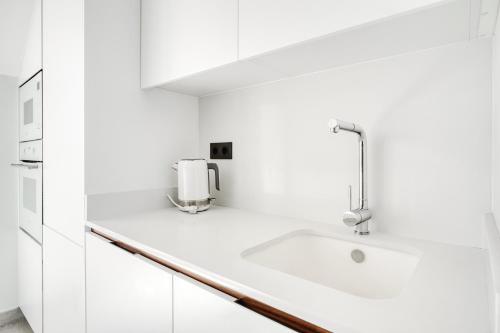 a white kitchen with a sink and a faucet at Casa Mar y Sol in Los Belones