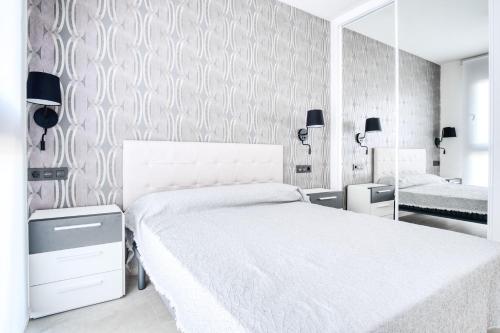 a bedroom with a white bed and a mirror at Casa Mar y Sol in Los Belones