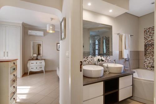 a white bathroom with two sinks and a tub and a tubermott at Casa das Buganvilias in Loulé