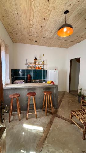 a kitchen with wooden stools and a counter with a refrigerator at Casa natureza Paraty II in Paraty