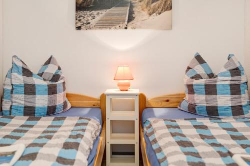 a twin bedroom with two beds and a lamp at Bungalow Mary Ann, Bgl 25 in Dranske