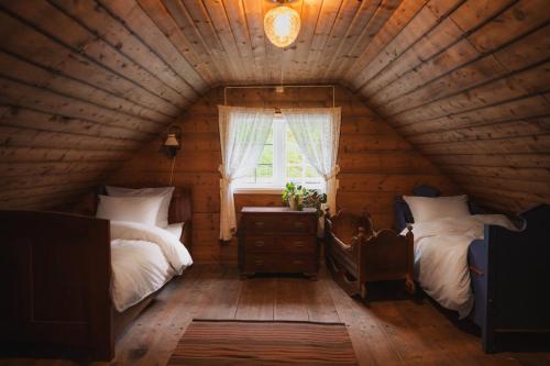 a room with two beds and a window in a log cabin at Aarvik organic farm & bakery in Tveit