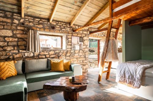 a living room with a green couch and a stone wall at Villa Nikos in Kefallonia