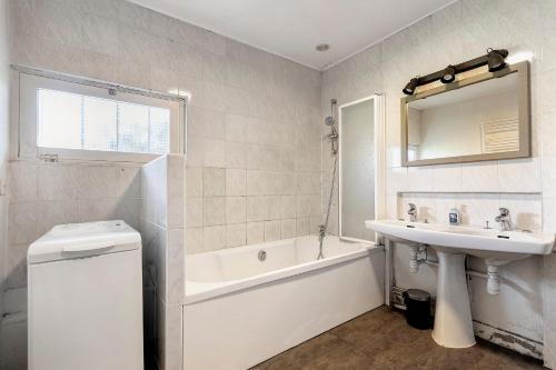 a white bathroom with a sink and a bath tub and a sink at Le Gîte du Château Saint Ahon in Blanquefort