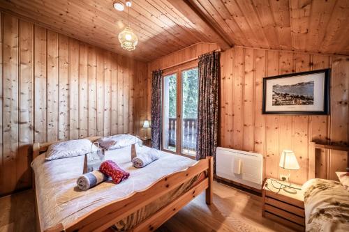 a bedroom with a bed in a wooden room at Chalet Des Charmes in Thollon
