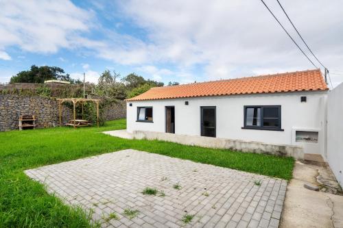 a white house with a green yard and a stone wall at Casa das Almas in Angra do Heroísmo
