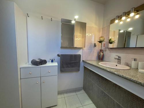 a white bathroom with a sink and a mirror at La Maison sur la côte in Fleury