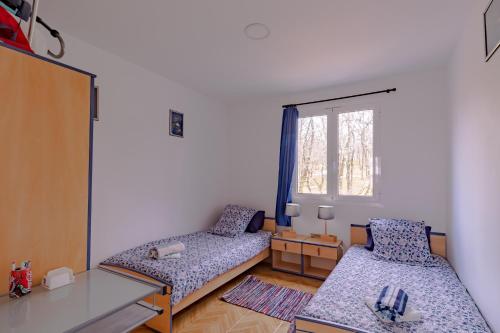 a small room with two beds and a window at Maison Sur le Causse Corrézien in Saint-Cernin-de-Larche