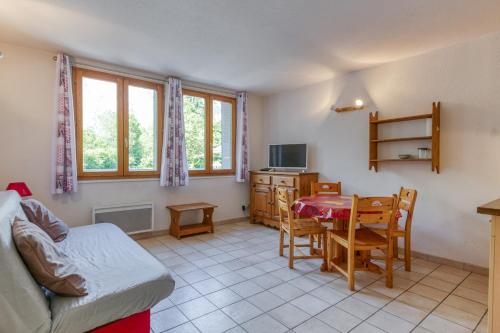 ein Wohnzimmer mit Tisch und Sofa sowie eine Küche in der Unterkunft Les Lys Orangés in Le Bourg d'oisans
