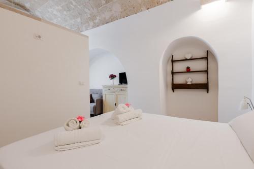 a white room with two towels on a bed at Luxury 12 in Tuglie