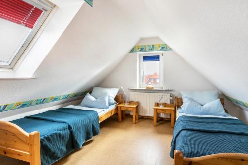 a attic room with two beds and a window at Bi uns to hus - Morgensünn in Nordstrand
