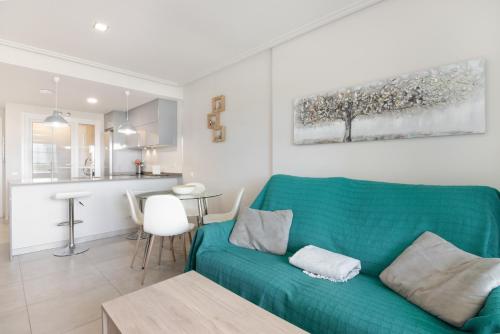 a living room with a green couch and a kitchen at Apartamento en Isla Canela in Ayamonte