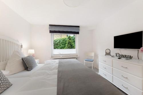 a white bedroom with a large bed and a flat screen tv at Ferienwohnung Angeln in Ulstrupfeld
