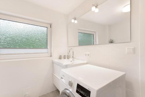 a white bathroom with a sink and a washing machine at Ferienwohnung Angeln in Ulstrupfeld