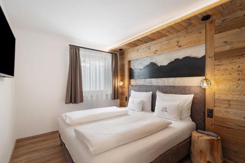 a bedroom with a large white bed with a wooden wall at Chalet-Suite Wiese in Selva dei Molini