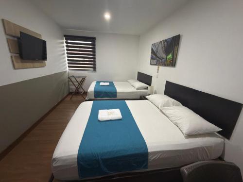 a hotel room with two beds and a flat screen tv at Hotel Valle de San Nicolas in Rionegro