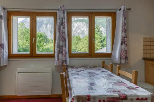 ein Schlafzimmer mit einem Bett und zwei Fenstern in der Unterkunft Les Lys Orangés in Le Bourg d'oisans