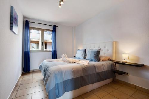 a bedroom with a bed with blue curtains and a window at Apartamento Relax and Dream in Pájara