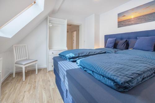 a bedroom with two blue beds and a chair at Ferienwohnung Stella Maris in Carrenzien