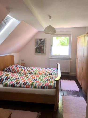 a bedroom with a bed with a colorful comforter and a window at Mein Ferienhaus Rosenbusch 2 in Kemmern
