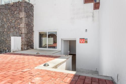 a white building with a window and a brick floor at Tea-Rose Loft in Conil