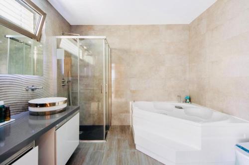 a bathroom with a large white tub and a shower at Ria Lounge House in Torreira