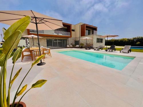 a villa with a swimming pool and a house at Ria Lounge House in Torreira