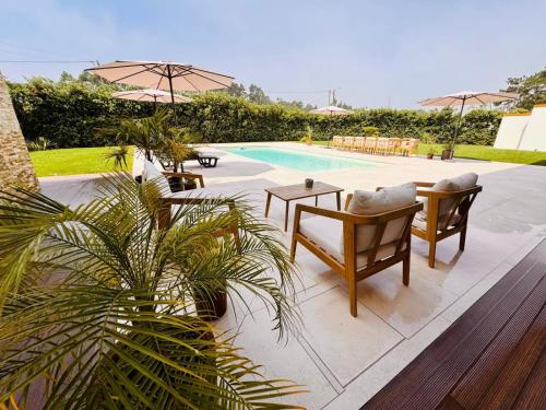 a patio with chairs and a table and a pool at Ria Lounge House in Torreira