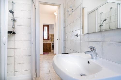 a white bathroom with a sink and a mirror at Villa Francesco P Terra in Orosei