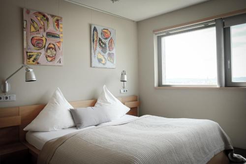 a bedroom with a bed with white sheets and a window at Gästehaus im Weingut am Stein in Würzburg