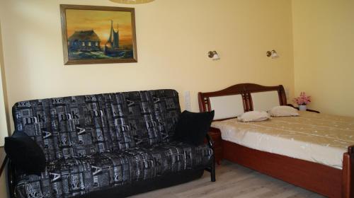 a bedroom with a bed and a couch and a painting at VilaFėja Private courtyard house in Palanga