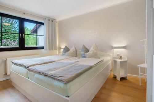 a white bedroom with a large bed with a window at Ferienwohnung To Hus in Putbus