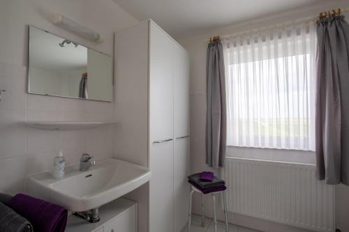 a white bathroom with a sink and a mirror at Vogelhus Yvonne Vogel in Pellworm