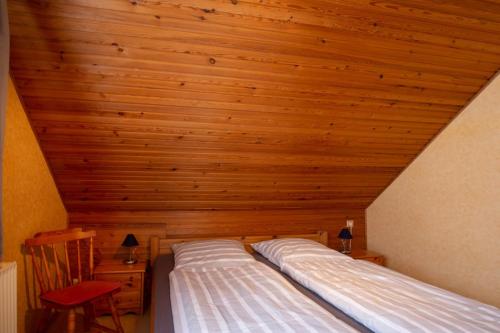 two beds in a room with a wooden ceiling at Vogelhus Yvonne Vogel in Pellworm