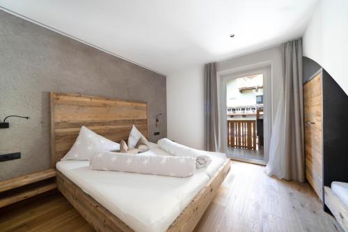 a bedroom with a large white bed with a wooden headboard at Sonnleiten Sterngucker 10 in Collepietra