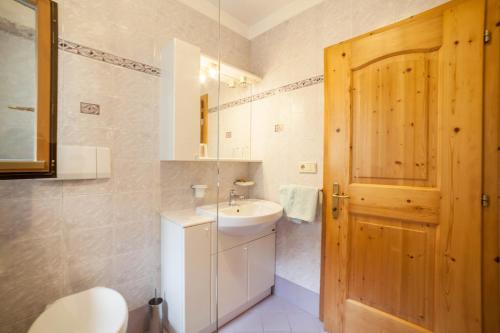 a bathroom with a sink and a wooden door at Sonnenparadies Apartement 1 in Saltusio