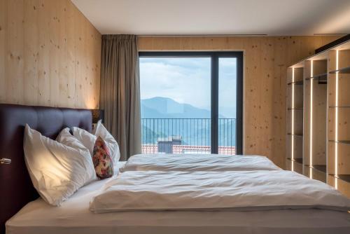 a bedroom with a large bed with a large window at Aumia Apartment Turmalin in Völs am Schlern