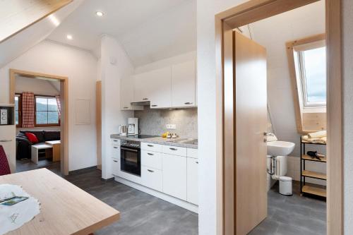 a kitchen with white cabinets and a wooden table at Löcherhansenhof in Bad Peterstal-Griesbach