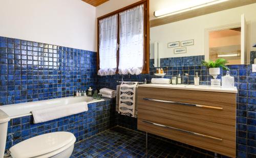 a blue tiled bathroom with a toilet and a sink at Chalet du cret in Lathuile