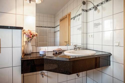 a bathroom with a sink and a vase of flowers at Schwalbennest in Buschvitz
