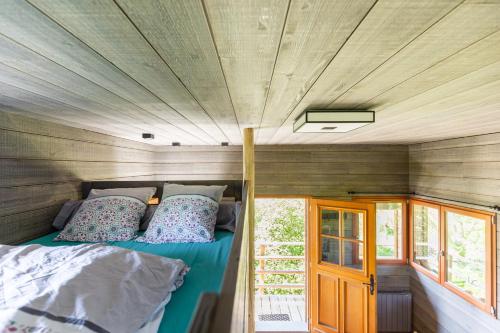 a bed in a tiny house with a wooden ceiling at La Cabane Perchée in Vert