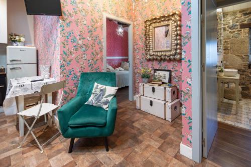 a living room with a green chair and pink wallpaper at La Caseta De Laura in Arzúa
