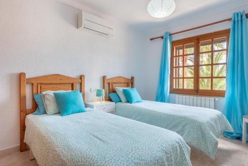 a bedroom with two beds and a window at Es Cantó in Cala Llombards