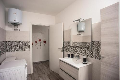 a bathroom with a sink and a toilet and a mirror at Villetta farfalle in Sarroch
