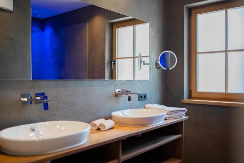 a bathroom with two sinks and a large mirror at Himml Schlosshof in Völs am Schlern