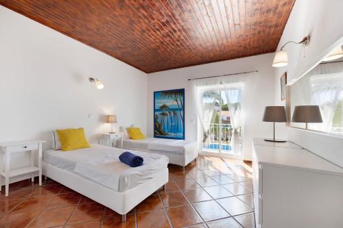 a bedroom with two beds and a table and a window at Villa Oliveira in Aljezur