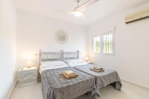 a white bedroom with a large bed with two towels on it at Villa Andes in Benissa