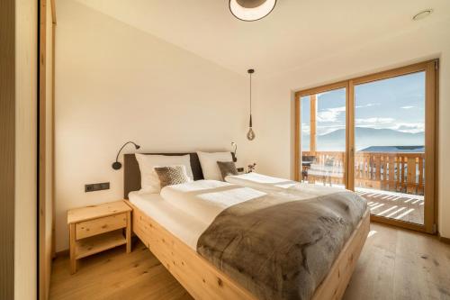 a bedroom with a large bed and a large window at Apt Eiche - Nockerhof in Andrian